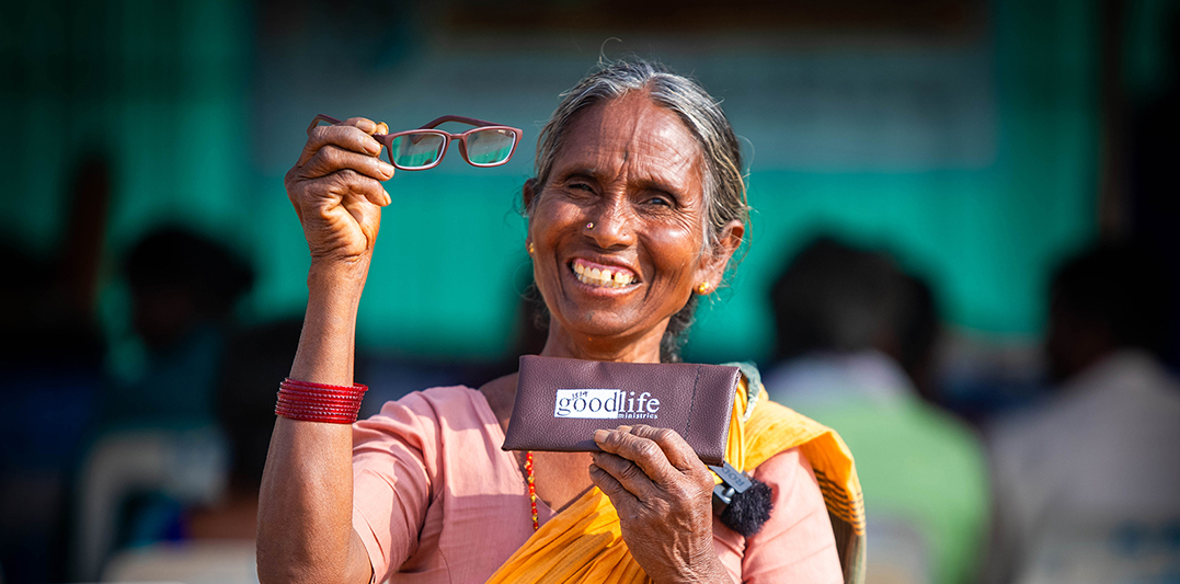 Smiling lady holding up glasses