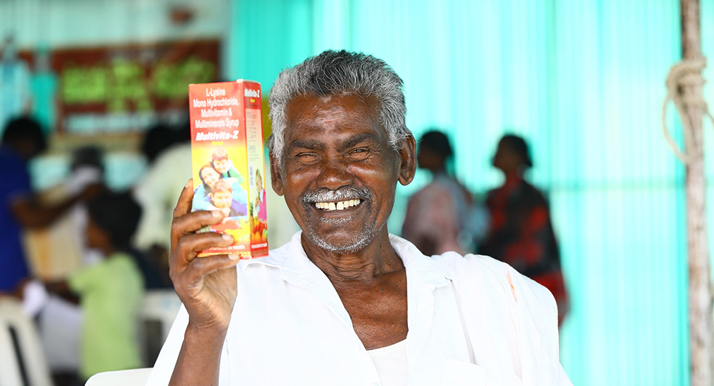 Elderly man happily shows a box of medicine
